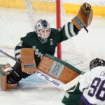 Boston goalie Aerin Frankel, left, grabs the puck for a save in front of Minnesota forward Michela Cava, right, during the third period of Game 1 of a PWHL hockey championship series, Sunday, May 19, 2024, in Lowell, Mass.